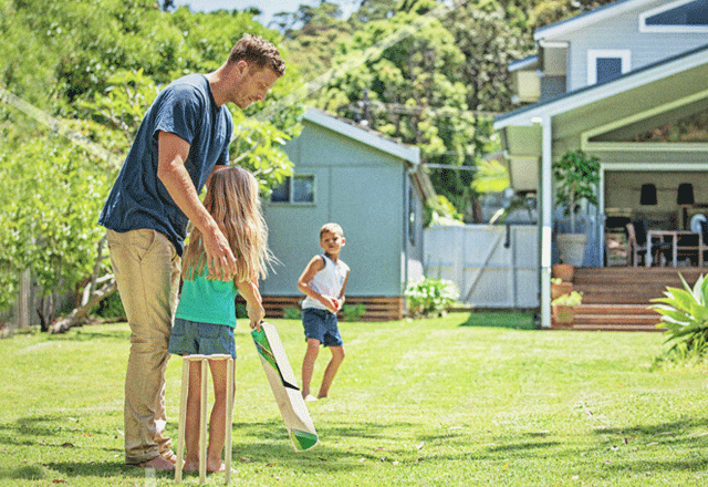 Family playing cricket in back yard.