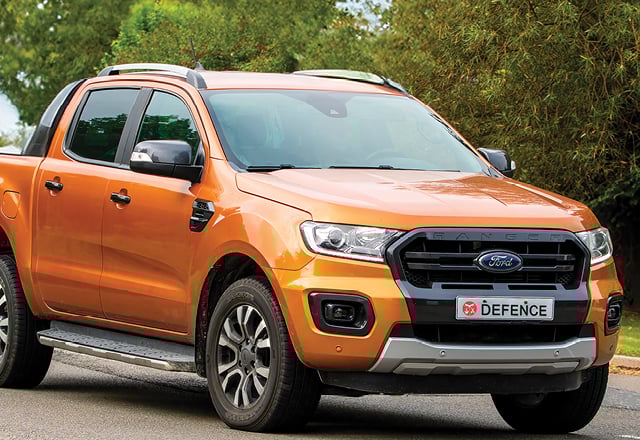 Orange four-door ute parked in a forested area