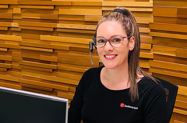 A smiling Defence Bank staff member wearing a headset.