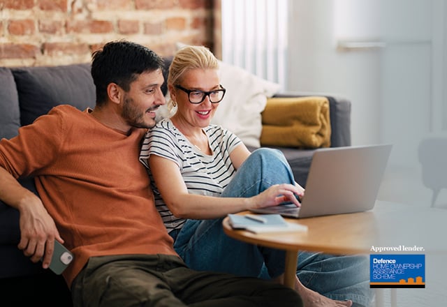 Young couple at home on the computer looking happy