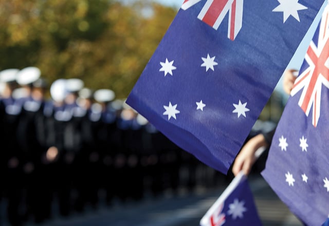 Australian flags against marching navy officers.