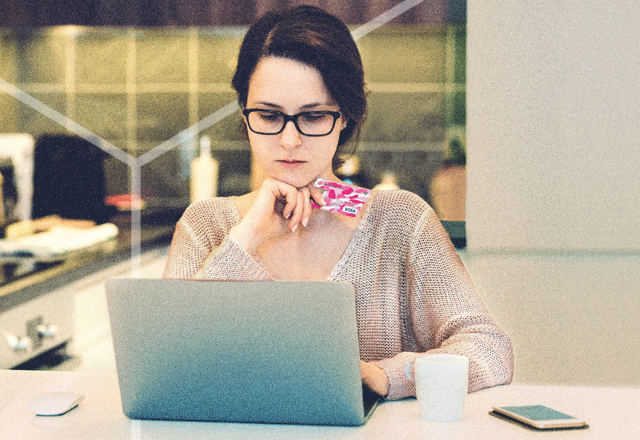 Woman holding credit card looking at laptop.