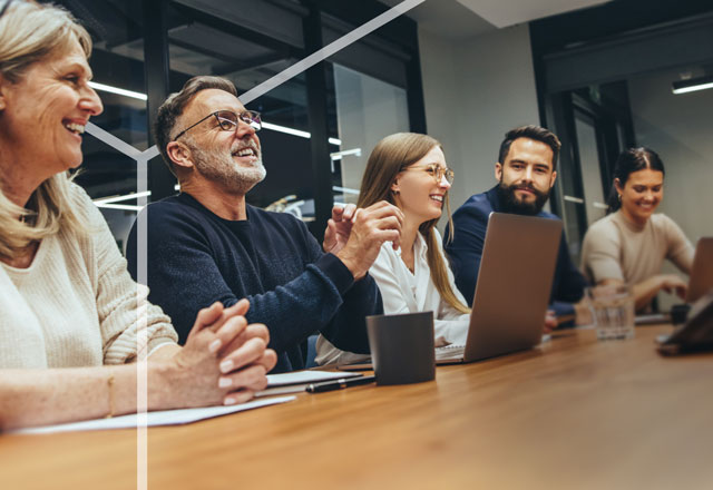 A group of male and female professionals enjoying a discussion in an office environment.