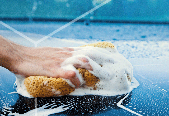 Soapy sponge being squeezed on a blue car.