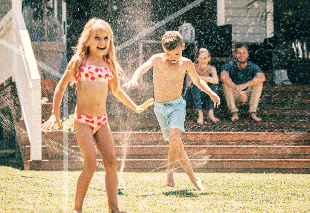 Kids playing in sprinkler.