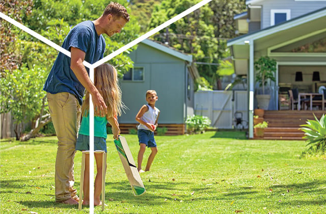 Family playing cricket in back yard.